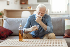 A man struggling with substance-related issues in older adults stares at a glass of alcohol in his hand.