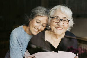 A woman embraces her elderly mother as she practices tips for dementia caregiving.