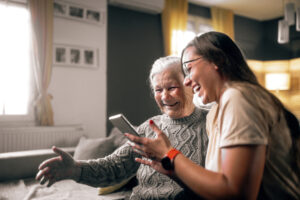 A caregiver is enhancing senior well-being with technology as she shows her elderly client how to use a new device.