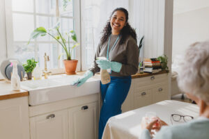 A professional caregiver helps her elderly client overcome home care hesitations by helping her maintain a clean and tidy home.