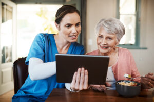 A nurse shows an older woman something on her tablet to help with her recovery after heart surgery.